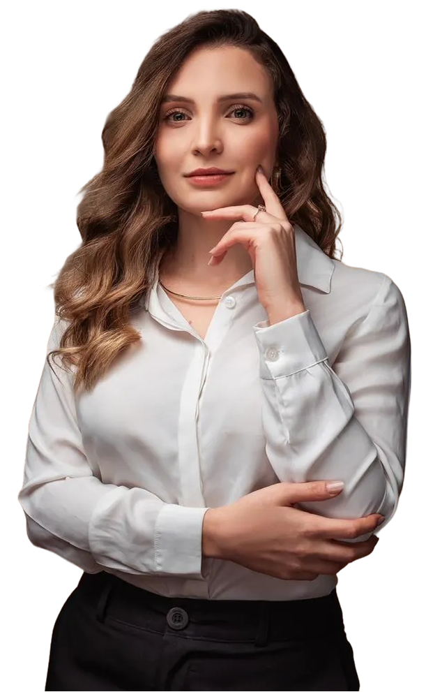 Mulher sorridente com cabelo castanho claro e longo, vestindo blusa de cetim marrom escuro e calça preta, em pé com os braços cruzados sobre fundo transparente.